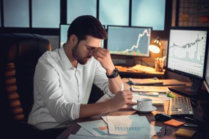 Man sitting at desk looking stressed with his head in his hand