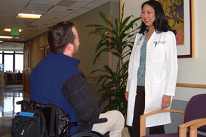 A doctor talking with a person in a wheelchair
