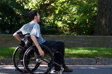 Person moving along sidewalk in wheelchair