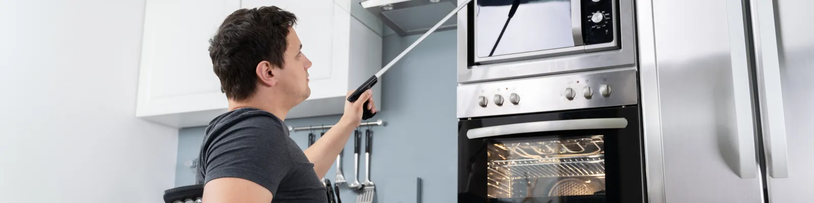 Photo of man in wheelchair reaching a high shelf with an assistive device