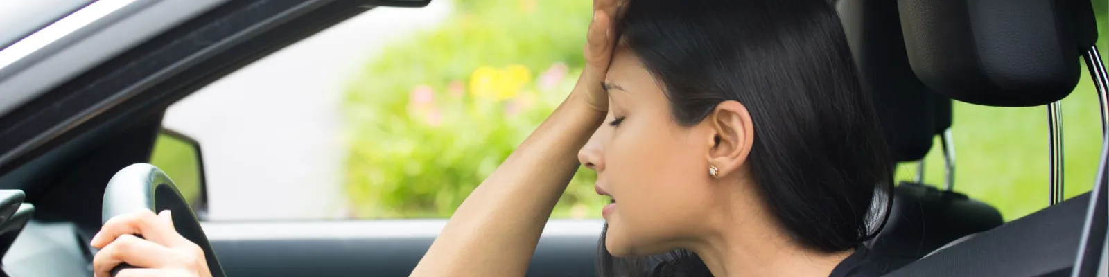 Photo of woman in vehicle holding her head