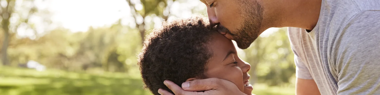 Photo of father kissing son on top of his head