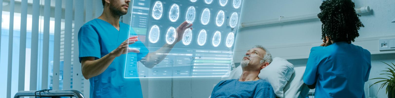 Photo of man in hospital bed with clinician looking at brain scans