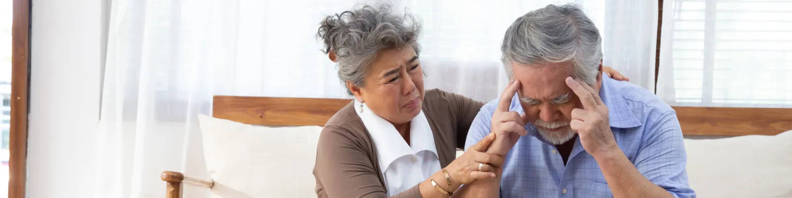 Photo of man holding his head with woman comforting him
