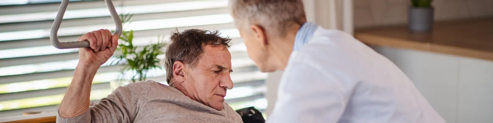 Photo of health care worker helping person move from bed