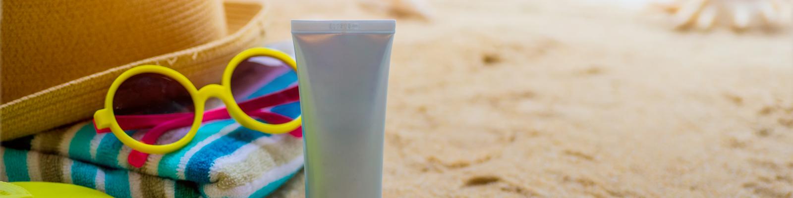 Photo of sunscreen and sunglasses on a beach
