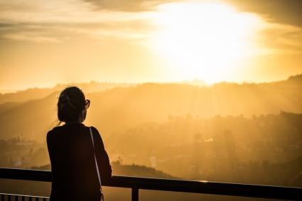 Silhouette of a person looking at a setting sun