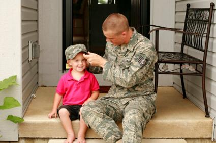 Military father putting his hat on his child