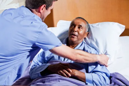 Nurse tending to a person lying in a hospital bed