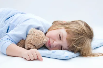 A young child lying down and frowning