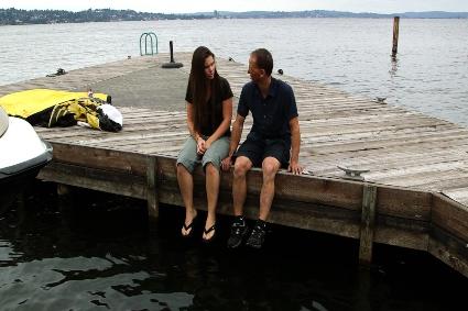 Two people sitting on a pier.