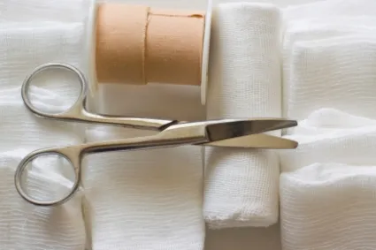 Gauze and scissors on plain background