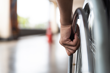 Image of a wheelchair wheel with a hand on it