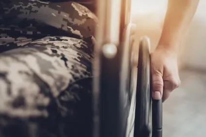 Person in military uniform sitting in a wheelchair.