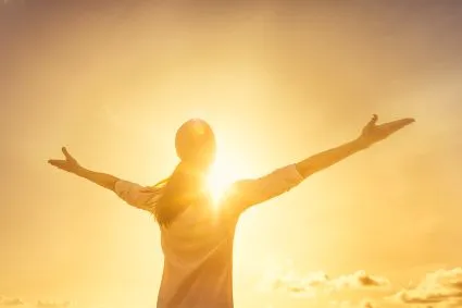 Person holding out their arms in the sunlight
