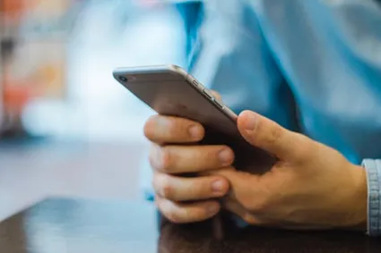 Person holding phone utilizing telehealth intervention