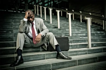 Person sitting next to briefcase on stairs and looking upset