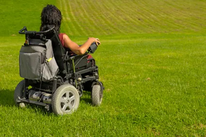 Person using power wheelchair in a grass field