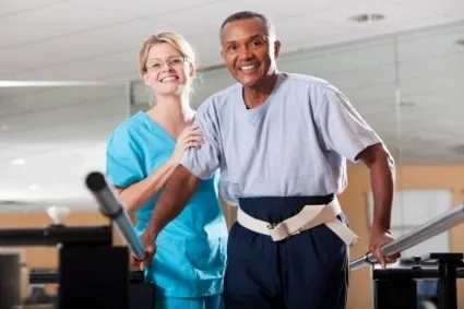 Man being guided by trainer during rehabilitation.