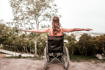Person sitting in wheelchair looking at view with arms raised out to the sides.