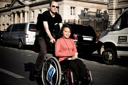 Person walking behind friend in wheelchair 