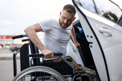 Photo of man transferring from wheelchair to vehicle