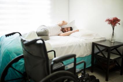 Photo of man in bed with wheelchair beside the bed