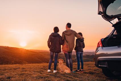 Photo of family looking into sunset, standing outside vehicle