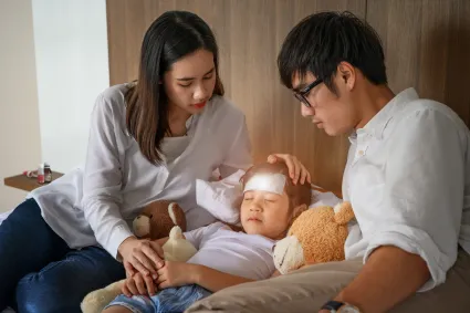 Photo of parents taking care of child with bandage on the head
