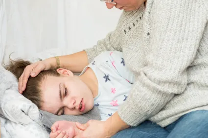 Photo of child with TBI in bed with caregiver beside them