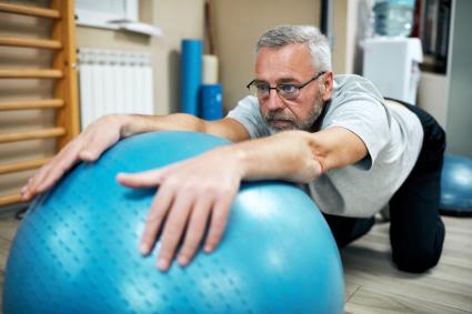 Man practicing balancing with exercise ball