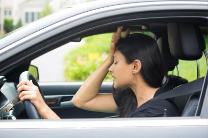 Photo of woman in vehicle holding her head
