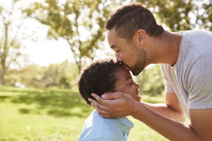 Photo of father kissing son on top of his head
