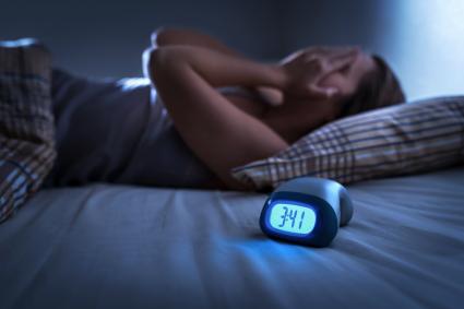 Photo of person awake in bed beside a clock that reads 3:41