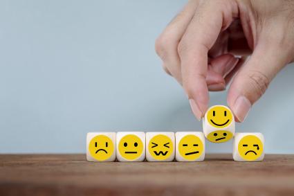 Photo of faces on blocks with different emotions and someone turning the smile over