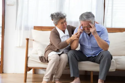 Photo of man holding his head with woman comforting him