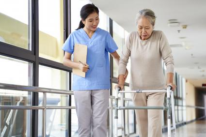 Health care working helping woman with walker walk