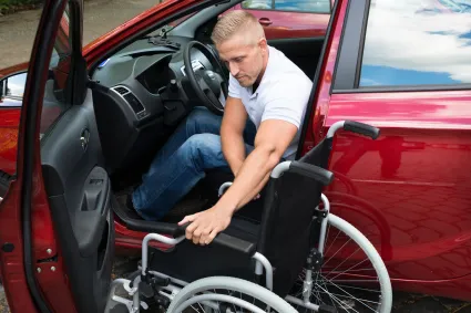 Man transferring from wheelchair to vehicle driver seat