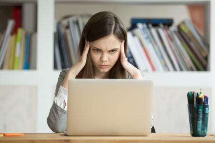 Photo of woman at computer holding her head