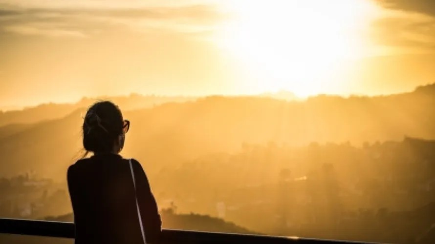 Silhouette of a person looking at a setting sun