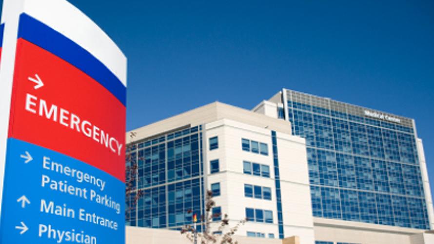 Entrada frontal de un hospital que muestra una señal de emergencia