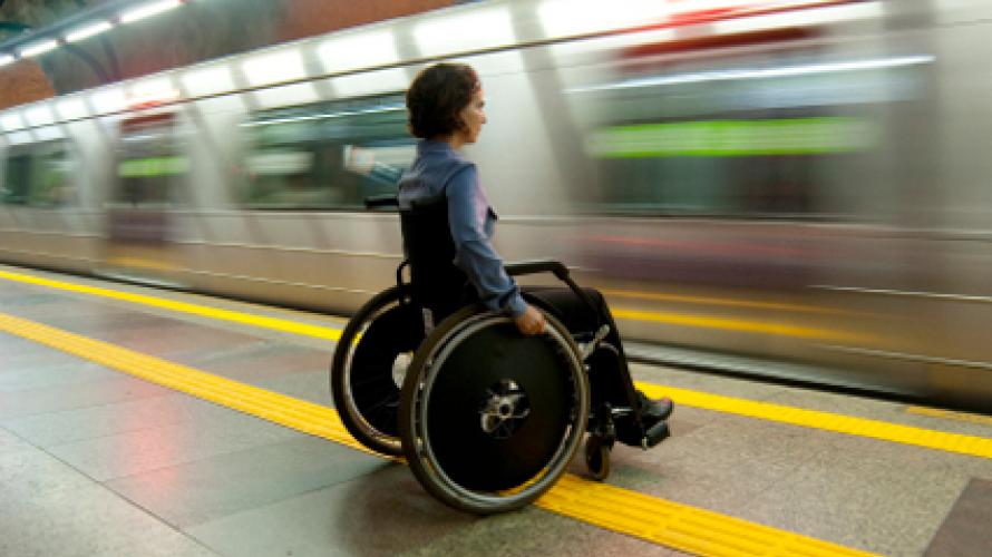 Person in a wheelchair in a subway station as a train rushes past