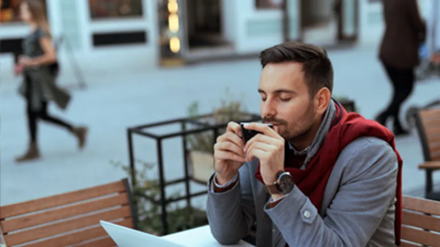 Hombre en café oliendo taza de café