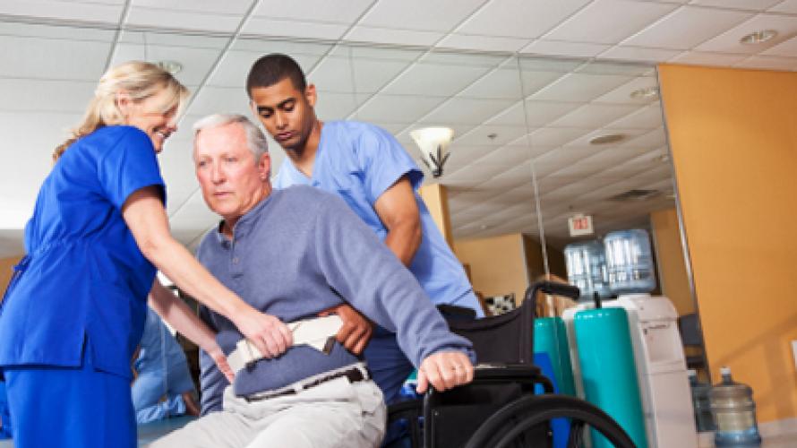 Dos enfermeras ayudando a un hombre a salir de una silla de ruedas