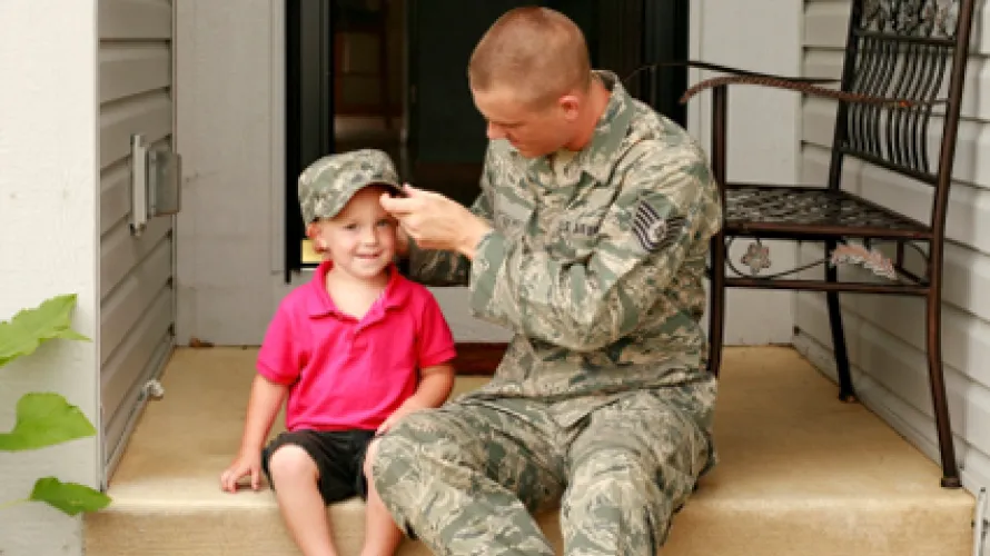Military father putting his hat on his child