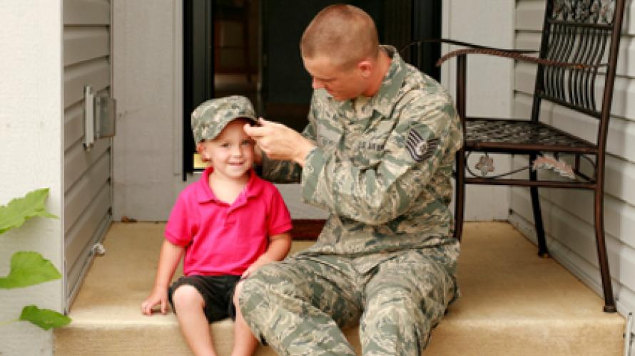 Padre militar poniendo su sombrero en su hijo