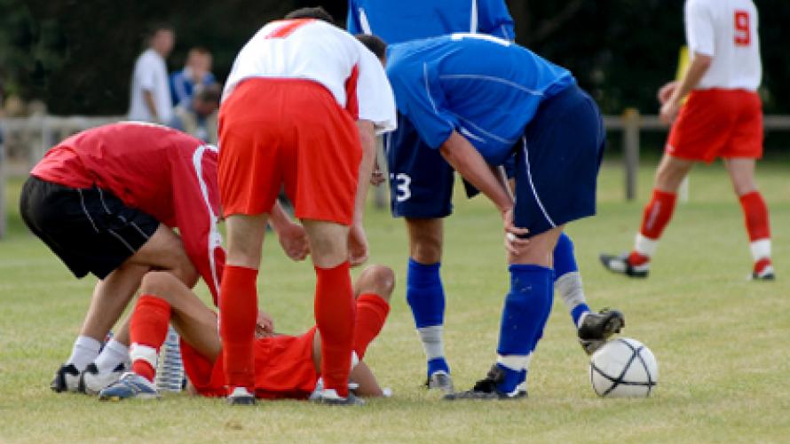 Soccer players huddled around injured teammate
