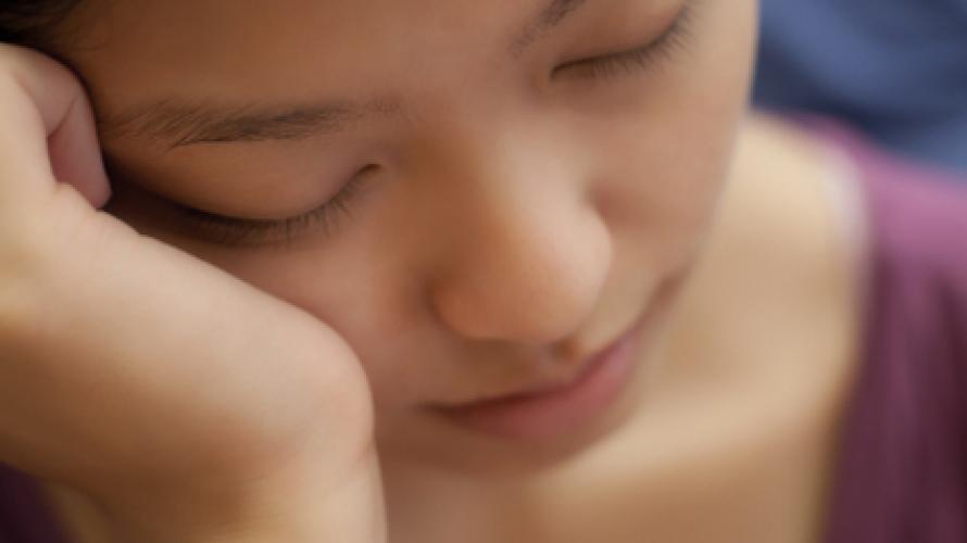 Close-up of a tired person resting their head on their hand