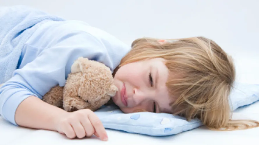 Un niño pequeño acostado en la cama y frunciendo el ceño