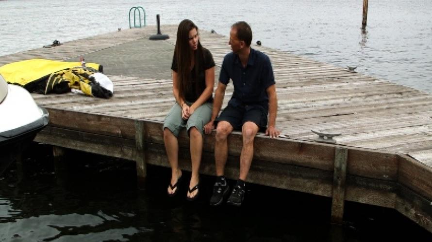 Two people sitting on a pier.